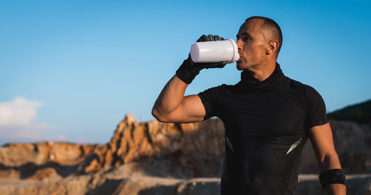 Sweaty guy drinking water out in desert during workout